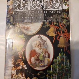 以下が含まれることがあります： 「Christmas Joy」と題されたIron Orchid Designsの転写シートのパッケージ。パッケージは、サンタクロース、ベル、クリスマスツリーなど、クリスマスのテーマのイラストが描かれた黒い背景が特徴です。シートのサイズは20.3cm x 30.5cmです。