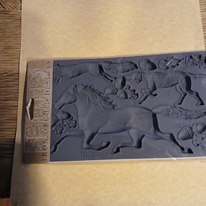 Może przedstawiać: Niebieska silikonowa forma z szczegółowymi wzorami reliefowymi biegnącego konia, psów i liści. Na opakowaniu widnieje napis "IRON ORCHID DESIGNS" i "HORSE & HOUND". Forma ta służy prawdopodobnie do tworzenia elementów dekoracyjnych do rękodzieła.