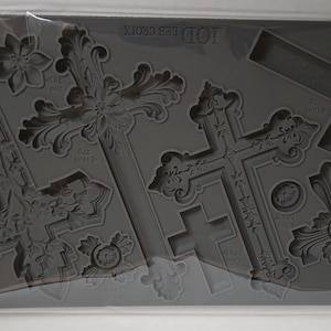 Könnte beinhalten: Eine graue Silikonform mit verschiedenen Kreuzdesigns, von aufwendigen bis zu schlichten Stilen. Die Form ist mit "Iod Les Croix" und "Iron Orchid Designs" beschriftet. Die Kreuze variieren in Größe und Detail, geeignet für Bastelprojekte.