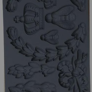 Puede incluir: Un molde de silicona gris oscuro con varios elementos decorativos. El molde incluye coronas de laurel, coronas, formas de abeja y un lazo. El texto "IRON ORCHID DESIGNS" y "LAUREL" son visibles.