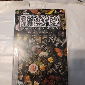 May include: A package of Iron Orchid Designs transfer sheets with a floral and butterfly design. The package contains eight sheets, each measuring 20.3 cm x 30.5 cm. The design features flowers and butterflies in pink, orange, yellow, and blue on a black background.