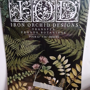 Può includere: Fogli di trasferimento Iron Orchid Designs con fronde botaniche. La confezione contiene quattro fogli da 30,5 cm x 40,6 cm. Il design presenta illustrazioni di felci e foglie in verde, marrone e rosa su sfondo nero.