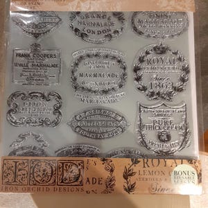 Puede incluir: Sellos de goma transparentes con varios diseños de etiquetas de estilo vintage. Los sellos presentan textos como "Orange Marmalade London", "Royal Lemon Curd" y "Potted Meats". Los sellos están empaquetados en una lámina de plástico transparente.