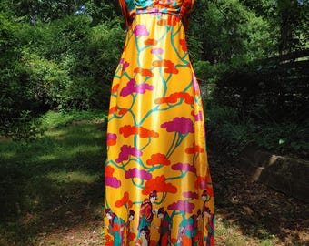 May include: A vibrant, floor-length dress with a mandarin collar. The dress features a yellow background with a colorful floral and figure pattern. The bodice has a multi-colored floral design, and the dress is displayed on a mannequin.