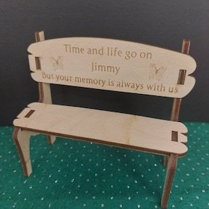 May include: A wooden bench with a carved inscription that reads "Time and life go on Jimmy But your memory is always with us". The inscription is surrounded by two butterfly designs.