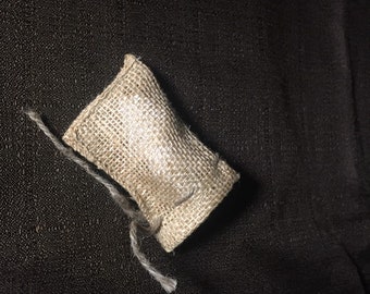 May include: A small, brown burlap pouch with a drawstring closure. The pouch is tied with a thin, white string.