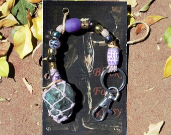 Cintre pour sac ou clés couleurs violettes avec roche en verre vert pâle dans un filet Mauve