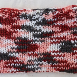 May include: A knitted fabric swatch with a plaid pattern in shades of red, pink, white, and gray.