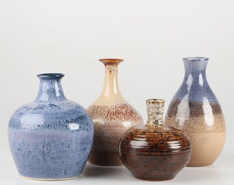 May include: Four ceramic vases in different colors and patterns. The vases are all different shapes and sizes. The vases are on a white background.