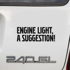 Może przedstawiać: Biały Volvo 240 GL kombi z czarnym zderzakiem i tablicą rejestracyjną z napisem "359". Czarna naklejka z tyłu głosi "Engine Light, A Suggestion!"