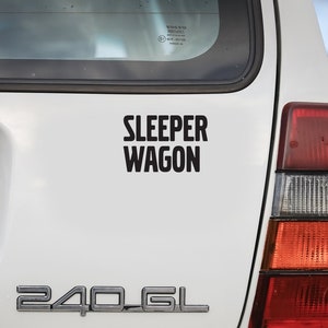 May include: A white Volvo 240 GL station wagon with a black "Sleeper Wagon" sticker on the back. The car has a license plate that reads "359".