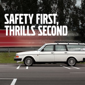 Op de afbeelding: Een witte Volvo stationwagen met een dakrek geparkeerd op een parkeerplaats. De auto heeft een sticker op de achterruit met de tekst "Safety First, Thrills Second".