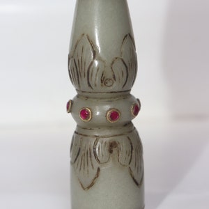May include: A pale green, carved jade bottle stopper with gold accents and red gemstone embellishments. The stopper features a floral design and is approximately 5 inches tall.