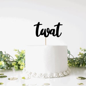 Könnte beinhalten: Ein weißer Kuchen mit einem schwarzen, kursiv geschriebenen "twat"-Kuchentopper.