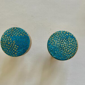 May include: A pair of round, turquoise earrings with a gold speckled pattern.