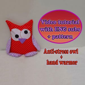 May include: A handmade red owl-shaped plush toy with white polka dots, large button eyes, and a purple beak. The owl has lavender and white checkered wings and feet. Text on the image reads "Video tutorial with ENG subs + pattern" and "Anti-stress owl + hand warmer."