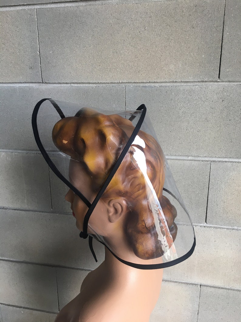 Op de afbeelding: Een transparant plastic vizier met een zwarte rand. Het vizier wordt gedragen op een mannequinhoofd.