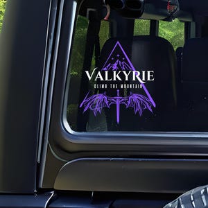 May include: A purple and white car window sticker with the text "Valkyrie Climb the Mountain" and a stylized image of a mountain, wings, and a sword.