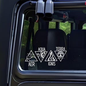 Op de afbeelding: Witte vinylsticker aangebracht op een autoraam. De sticker toont vier driehoekige symbolen die de elementen vertegenwoordigen: Lucht (AER), Water (AQUA), Vuur (IGNIS) en Aarde (TERRA). Elk element wordt afgebeeld met een unieke afbeelding.