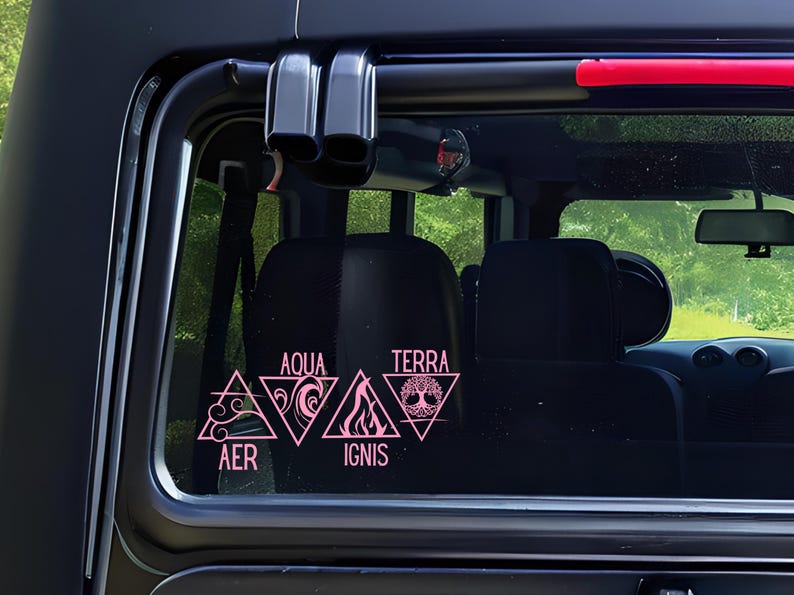 Op de afbeelding: Roze vinylstickers op een autoraam. De stickers tonen vier elementaire symbolen: Lucht (AER), Water (AQUA), Vuur (IGNIS) en Aarde (TERRA). Elk symbool staat in een driehoek, met de naam van het element erboven of eronder.