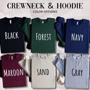 Puede incluir: Seis sudaderas de cuello redondo en diferentes colores: negro, verde bosque, azul marino, granate, arena y gris. Las sudaderas est&aacute;n dispuestas sobre una superficie texturizada.  CREW NECK & HOODIE COLOR OPTIONS est&aacute; escrito en la parte superior de la imagen.