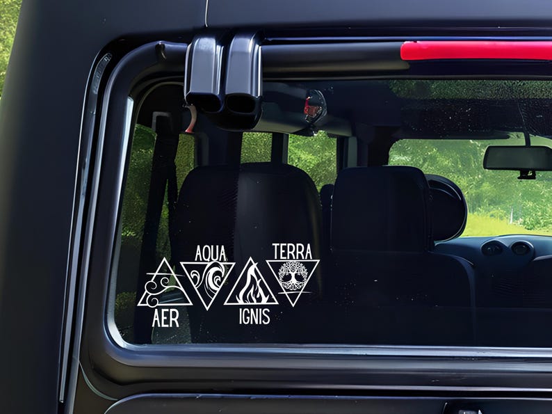 Op de afbeelding: Witte vinylsticker aangebracht op een autoraam. De sticker toont vier driehoekige symbolen die de elementen vertegenwoordigen: Lucht (AER), Water (AQUA), Vuur (IGNIS) en Aarde (TERRA). Elk element wordt afgebeeld met een unieke afbeelding.