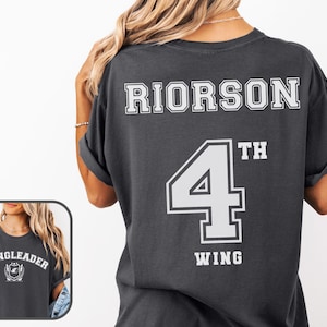 May include: A dark gray t-shirt with white text that reads "RIORSON 4TH WING" and "WINGLEADER" with a crest graphic.