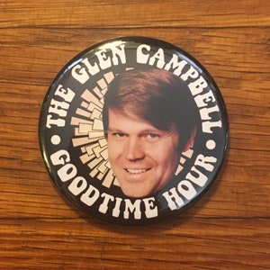 May include: A black and white button with a photo of Glen Campbell and the text "The Glen Campbell Goodtime Hour".