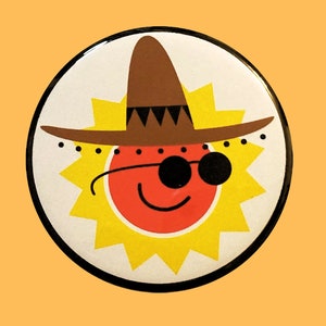 May include: A yellow sun with a red face wearing sunglasses and a brown sombrero.
