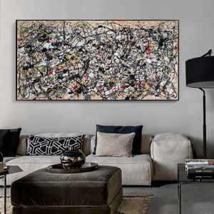 May include: Abstract painting in black, white, gray, yellow, and red on a beige canvas. The painting is framed in black and hanging on a wall above a gray sofa.