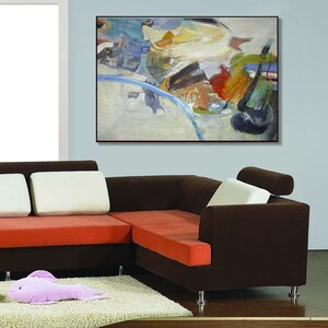 May include: A brown sectional sofa with orange cushions and a white throw pillow. The sofa is in front of a light blue wall with an abstract painting in a black frame.