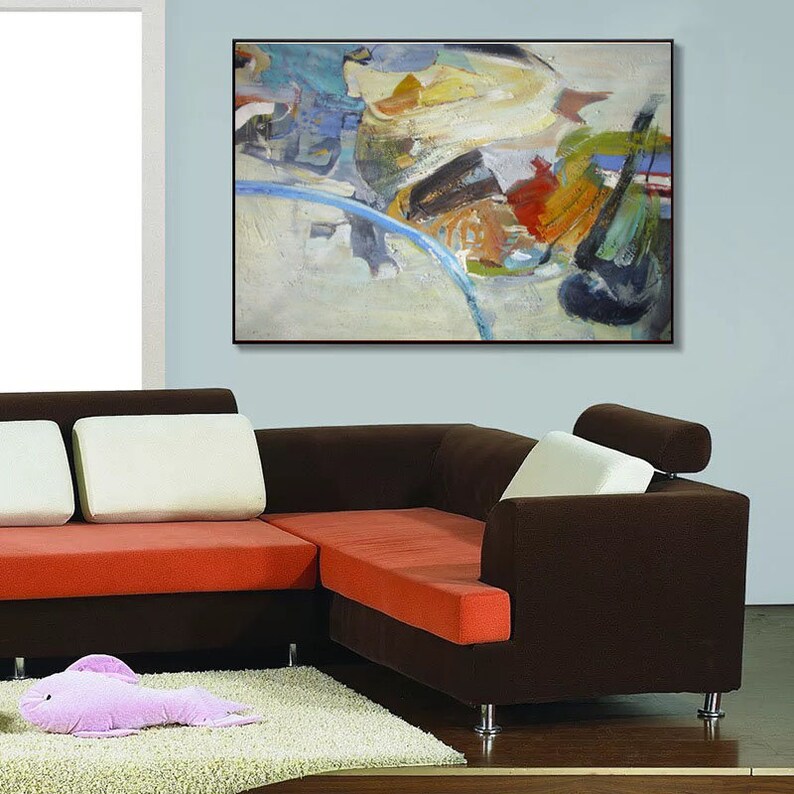 May include: A brown sectional sofa with orange cushions and a white throw pillow. The sofa is in front of a light blue wall with an abstract painting in a black frame.