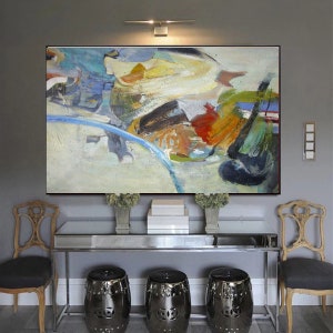 May include: Abstract painting with a mix of blue, green, yellow, orange, and red colors. The painting is hanging on a gray wall above a console table with three black stools.