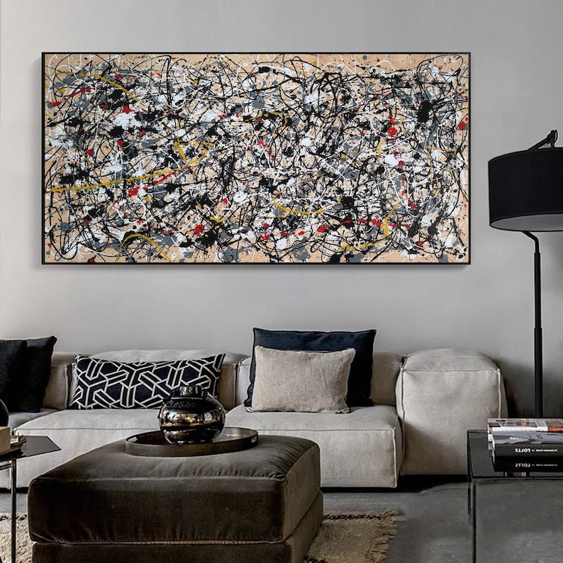 May include: Abstract painting in black, white, gray, yellow, and red on a beige canvas. The painting is framed in black and hanging on a wall above a gray sofa.