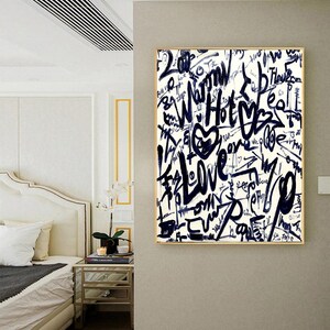 K&ouml;nnte beinhalten: Eine wei&szlig;e Leinwand mit goldenem Rahmen zeigt ein abstraktes Design in Schwarzwei&szlig; mit den W&ouml;rtern "Love", "Hot" und "Warm", die in Graffiti-Stil geschrieben sind.