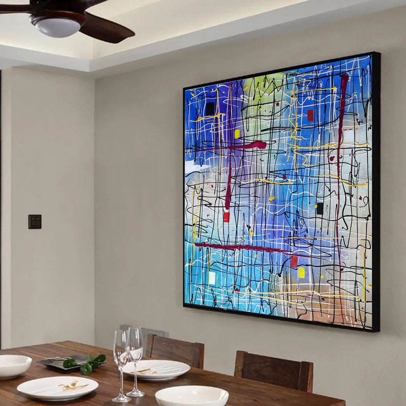 May include: Abstract painting with a black frame. The painting features a blue background with black, white, red, and yellow lines and shapes.