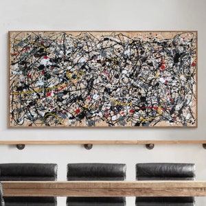 May include: Abstract painting with black, white, red, and yellow paint splatters and lines on a beige background. The painting is framed in a light wood frame.