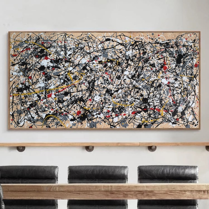 May include: Abstract painting with black, white, red, and yellow paint splatters and lines on a beige background. The painting is framed in a light wood frame.