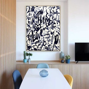 K&ouml;nnte beinhalten: Ein Schwarz-Wei&szlig;-Abstrakt-Kunstdruck mit goldenem Rahmen. Der Druck zeigt eine Vielzahl von W&ouml;rtern und Phrasen, die in einer fetten, Graffiti-Schrift geschrieben sind, darunter "Love", "Hot" und "Dream".