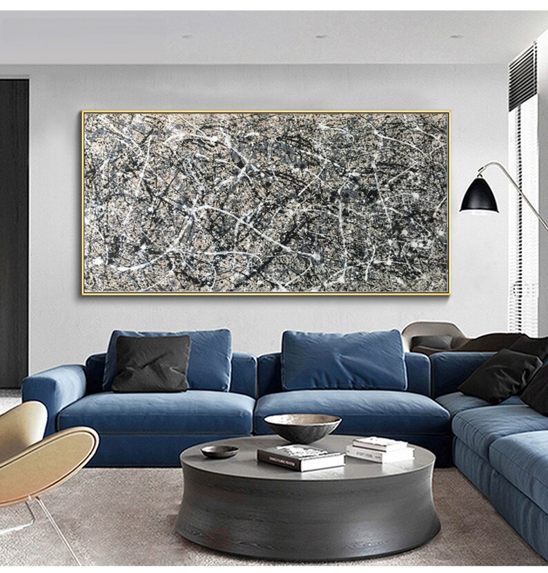 May include: Abstract art painting with black and white lines on a beige background. The painting is framed in a gold frame and is hanging on a wall above a blue sofa.