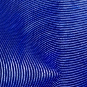 May include: A close-up of a blue textured surface with concentric circles. The surface is painted a deep blue color and has a raised, textured pattern.