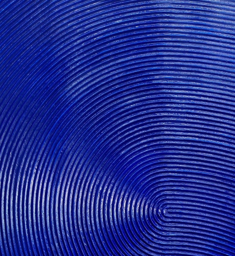 May include: A close-up of a blue textured surface with concentric circles. The surface is painted a deep blue color and has a raised, textured pattern.
