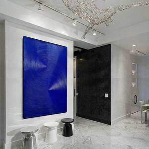 May include: A modern living room interior with a large blue abstract painting on the wall, three white and black side tables, and a white marble floor.
