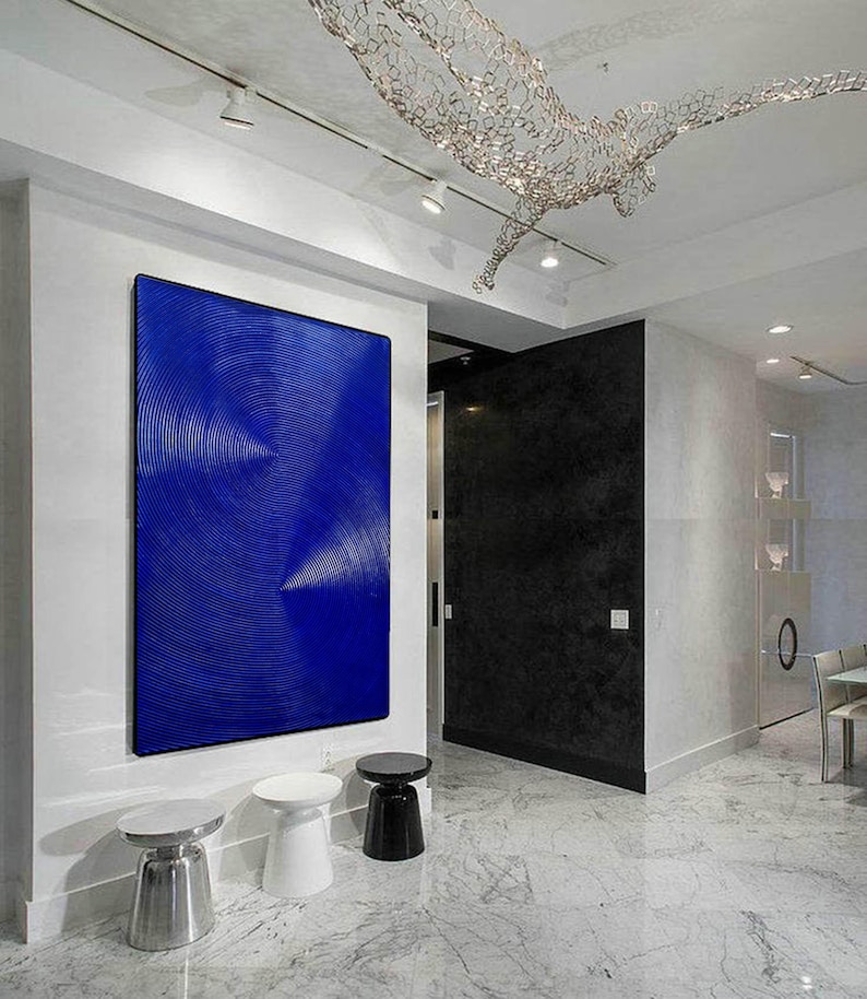 May include: A modern living room interior with a large blue abstract painting on the wall, three white and black side tables, and a white marble floor.