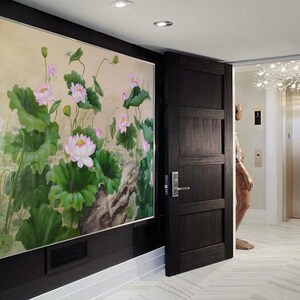 May include: A painting of pink lotus flowers and green leaves on a beige background. The painting is framed and hanging on a wall in a hallway.
