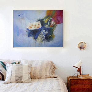 May include: Abstract painting with a blue, white, and green color scheme. The painting is framed and hanging on a white wall above a bed with pillows.