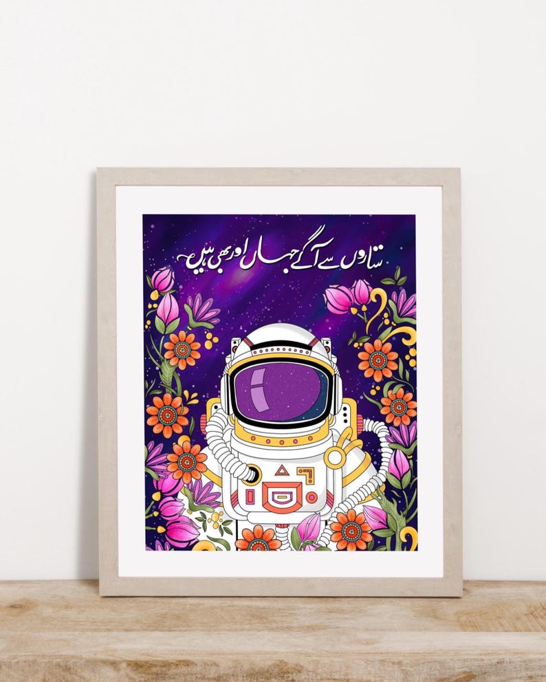 Urdu poetry art print featuring a female astronaut surrounded by floral motifs on a deep indigo background, displayed in a light wood frame.