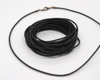 May include: A black leather cord necklace with a silver clasp. The cord is coiled up and ready to be used for jewelry making.