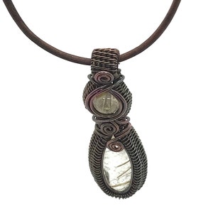 May include: A copper wire wrapped pendant necklace with a clear quartz stone. The pendant is in the shape of a teardrop and has a brown leather cord.