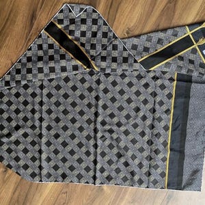 Peut inclure: Un foulard et une pochette assortis &agrave; motifs noirs et gris. Le foulard et la pochette pr&eacute;sentent un motif de losanges r&eacute;p&eacute;t&eacute;s avec des accents noirs et dor&eacute;s. Le foulard a une bande noire et dor&eacute;e au centre et une bordure blanche.